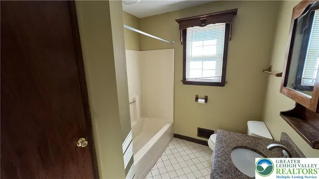 a bathroom with a granite countertop sink a toilet and shower