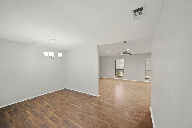 a view of empty room with wooden floor and kitchen