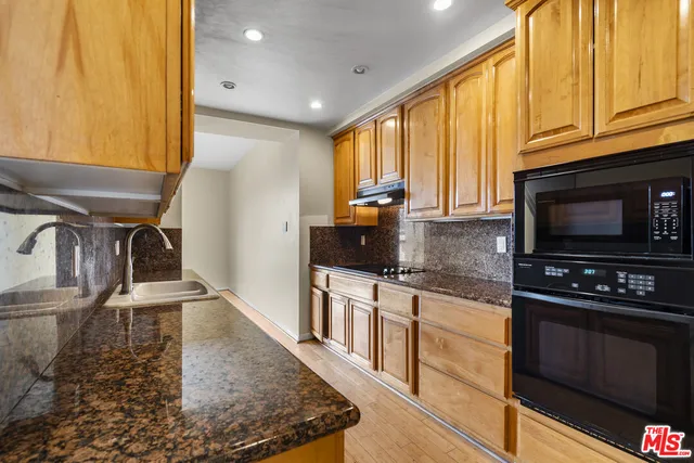 a kitchen with granite countertop a stove a sink and a microwave