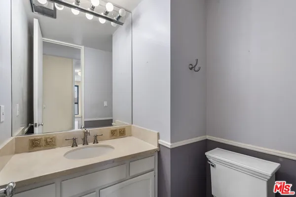 a bathroom with a granite countertop sink toilet and mirror