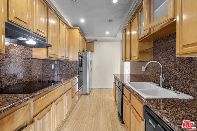 a kitchen with stainless steel appliances granite countertop a sink a stove and a wooden floors