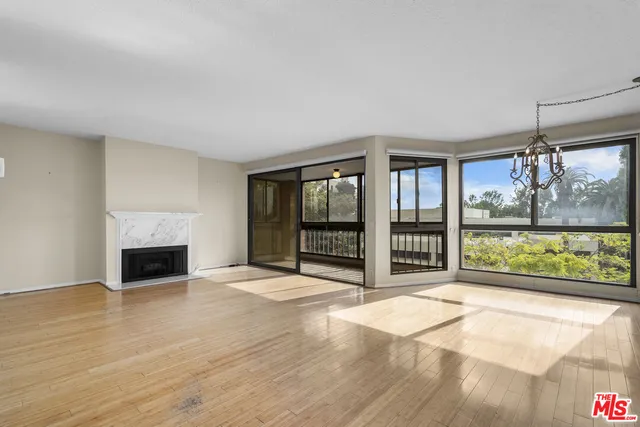 a view of an empty room with wooden floor and a fireplace