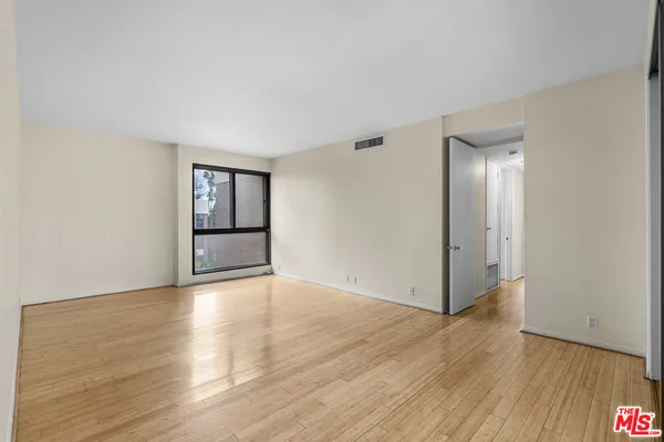a view of a big room with wooden floor and windows