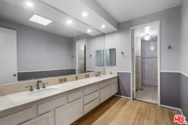 a bathroom with a double vanity sink and mirror with shower
