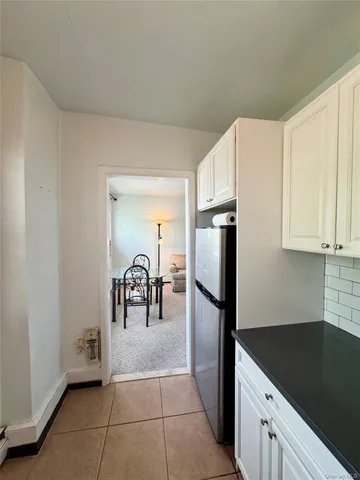 a kitchen with granite countertop a refrigerator a stove and white cabinets