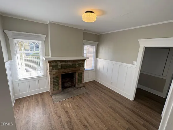 an empty room with wooden floor fireplace and windows