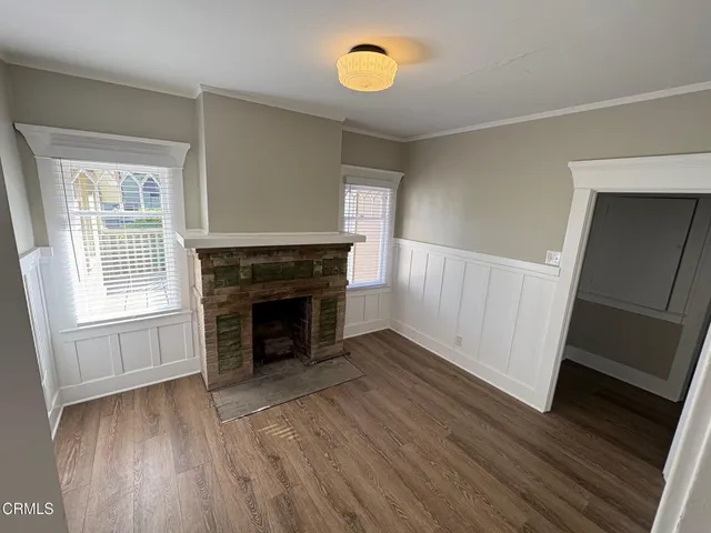 an empty room with wooden floor fireplace and windows