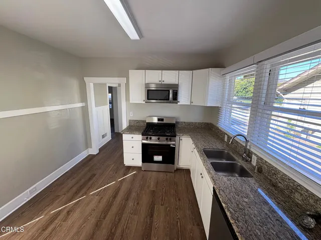 a kitchen with granite countertop a stove a sink and a refrigerator