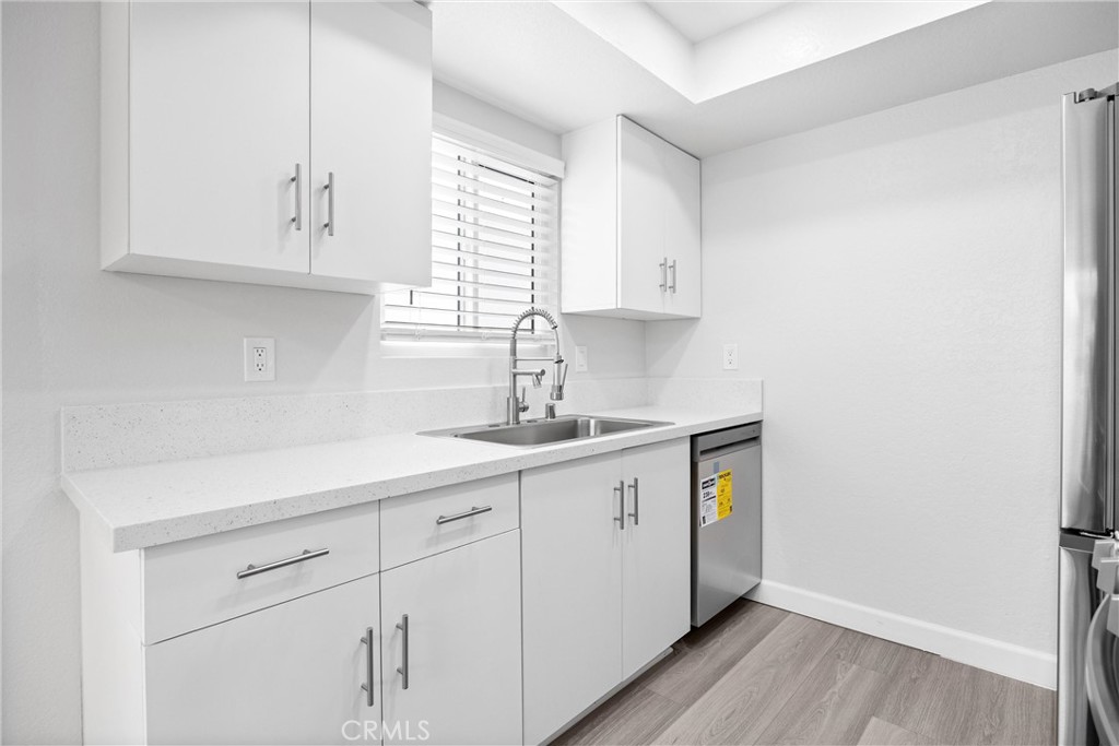 114 10th Street, Unit C Huntington Beach, CA 92648 - Photo 13 of 21 a kitchen with stainless steel appliances granite countertop white cabinets sink and window
