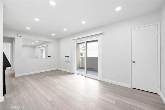 an entryway and an empty room with wooden floor