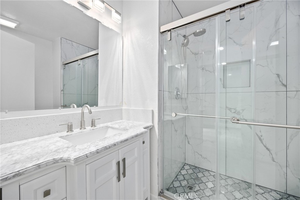 114 10th Street, Unit C Huntington Beach, CA 92648 - Photo 18 of 21 a bathroom with a granite countertop sink a shower and a mirror