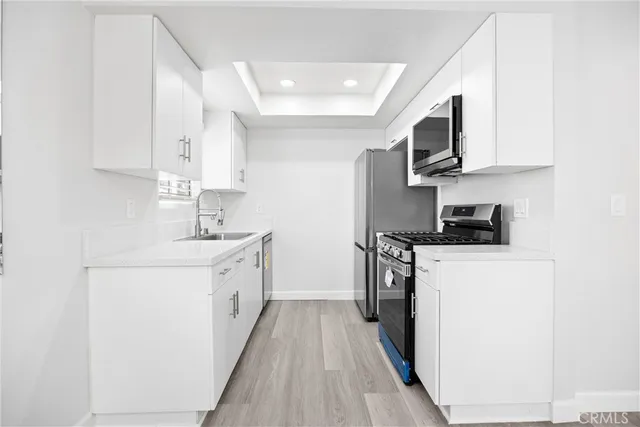 a kitchen with stainless steel appliances a sink stove top oven and white cabinets