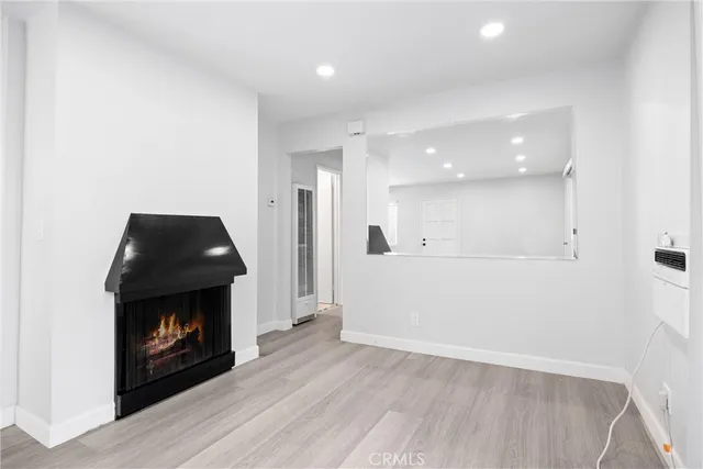 an entryway and an empty room with wooden floor