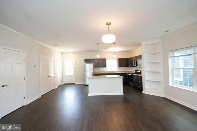 a kitchen with stainless steel appliances kitchen island wooden floors and white cabinets