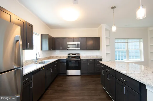 a kitchen with stainless steel appliances granite countertop refrigerator a sink a stove a microwave and wooden cabinets