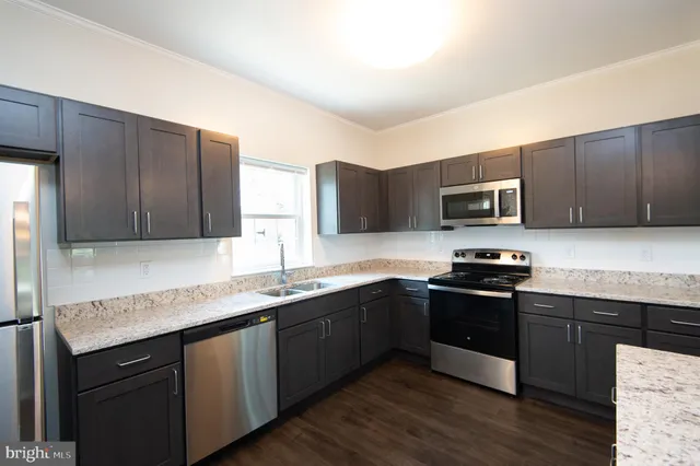 a kitchen with stainless steel appliances granite countertop wooden cabinets a stove top oven a sink and dishwasher with wooden floor