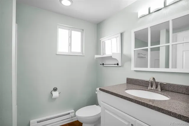 a bathroom with a granite countertop toilet a sink and mirror