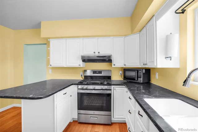 a kitchen with granite countertop a sink a stove and cabinets
