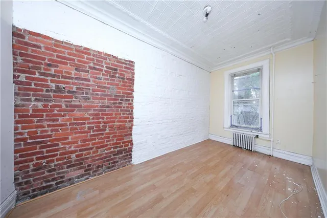 a view of an empty room with brick wall and a window