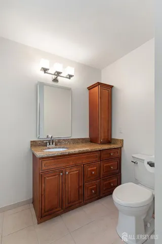a bathroom with a granite countertop toilet sink and mirror