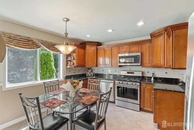 a kitchen with stainless steel appliances granite countertop a stove top oven a sink dishwasher a dining table and chairs with wooden floor