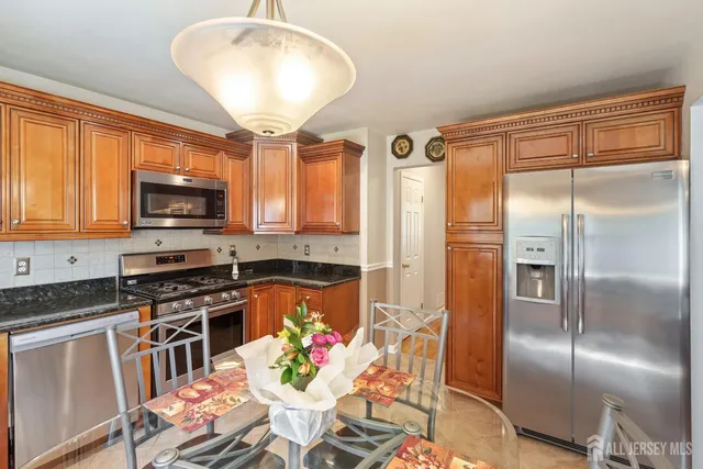 a kitchen with granite countertop stainless steel appliances a stove top oven a sink and a refrigerator