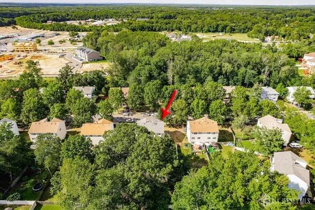 an aerial view of residential houses with outdoor space and trees all around