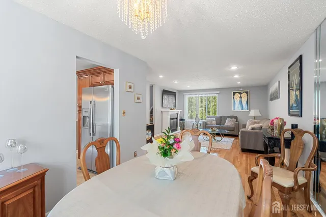 a dining room with furniture a potted plant and open kitchen view