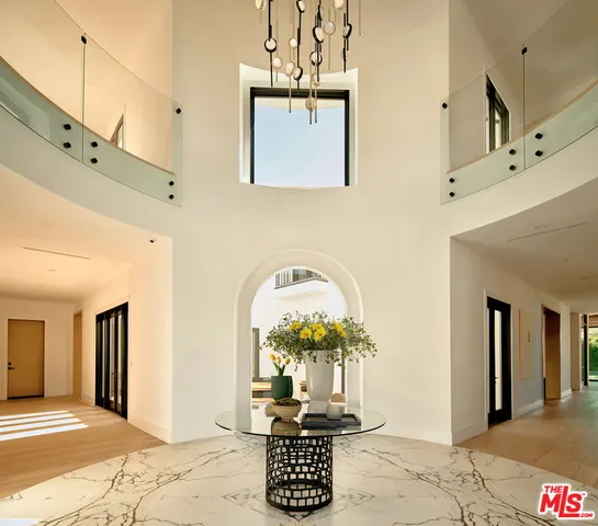 a view of a hallway with wooden floor windows and a chandelier