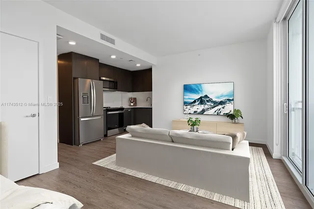 a living room with stainless steel appliances furniture a refrigerator and a sink