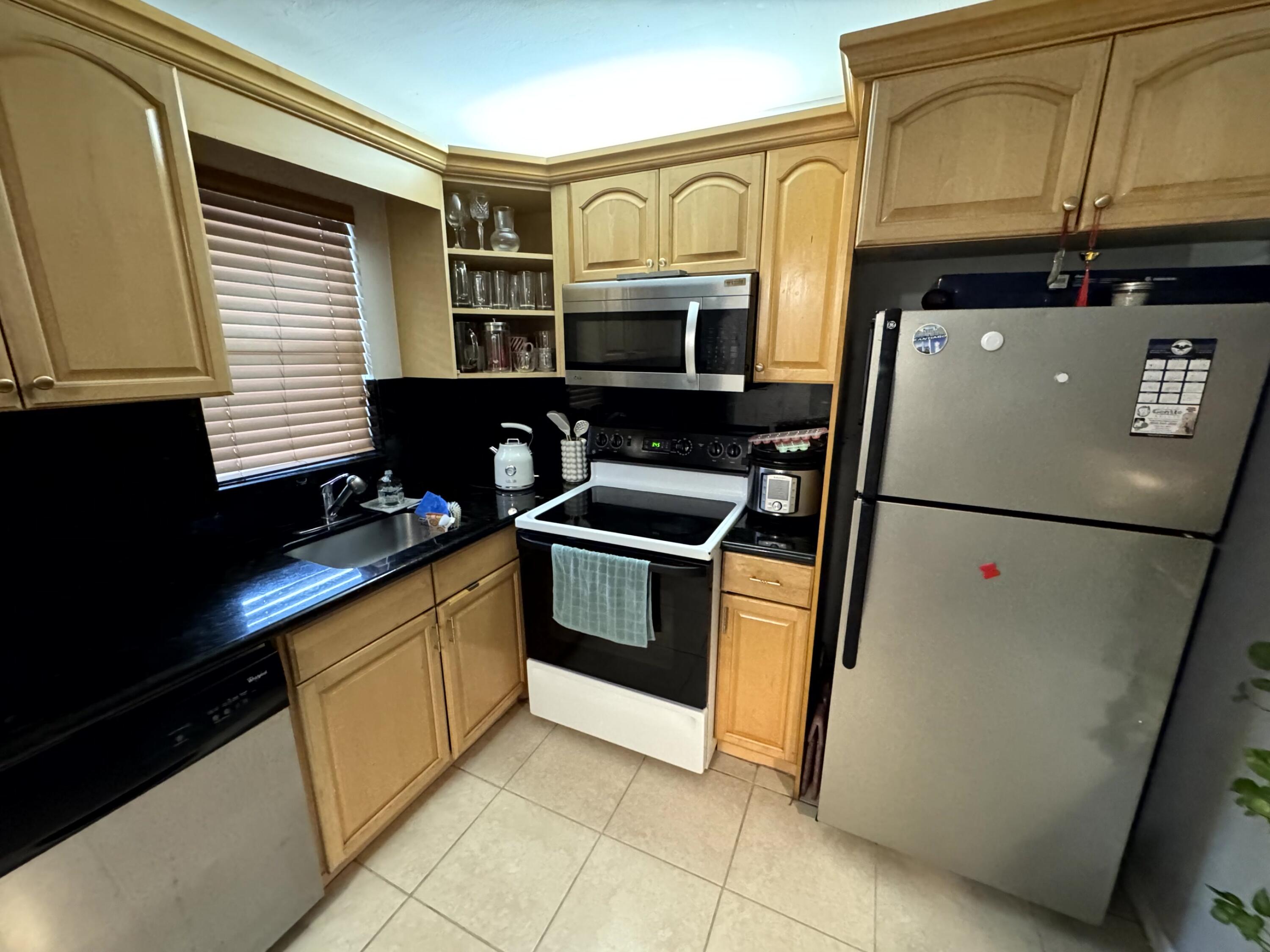 9355 Southwest 8th Street, Unit 102 Boca Raton, FL 33428 - Photo 1 of 1 a kitchen with stainless steel appliances a refrigerator sink and microwave