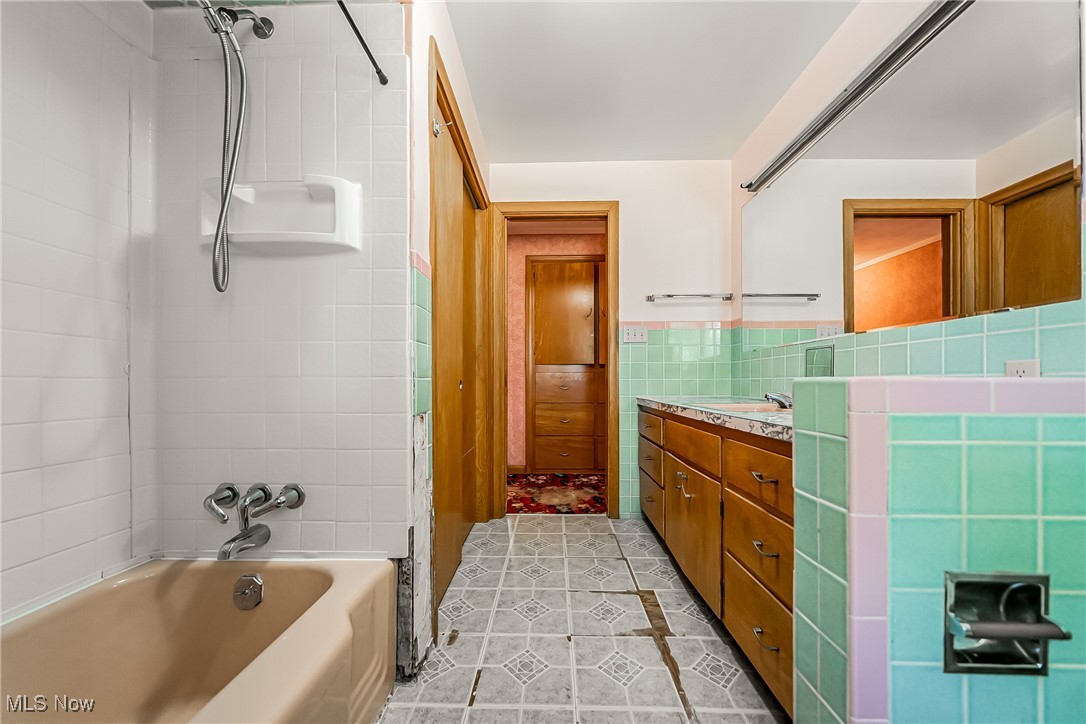 550 Cooper Foster Park Road Lorain, OH 44053 - Photo 26 of 50 Bathroom featuring shower / tub combo, vanity, light tile patterned flooring, and tile walls