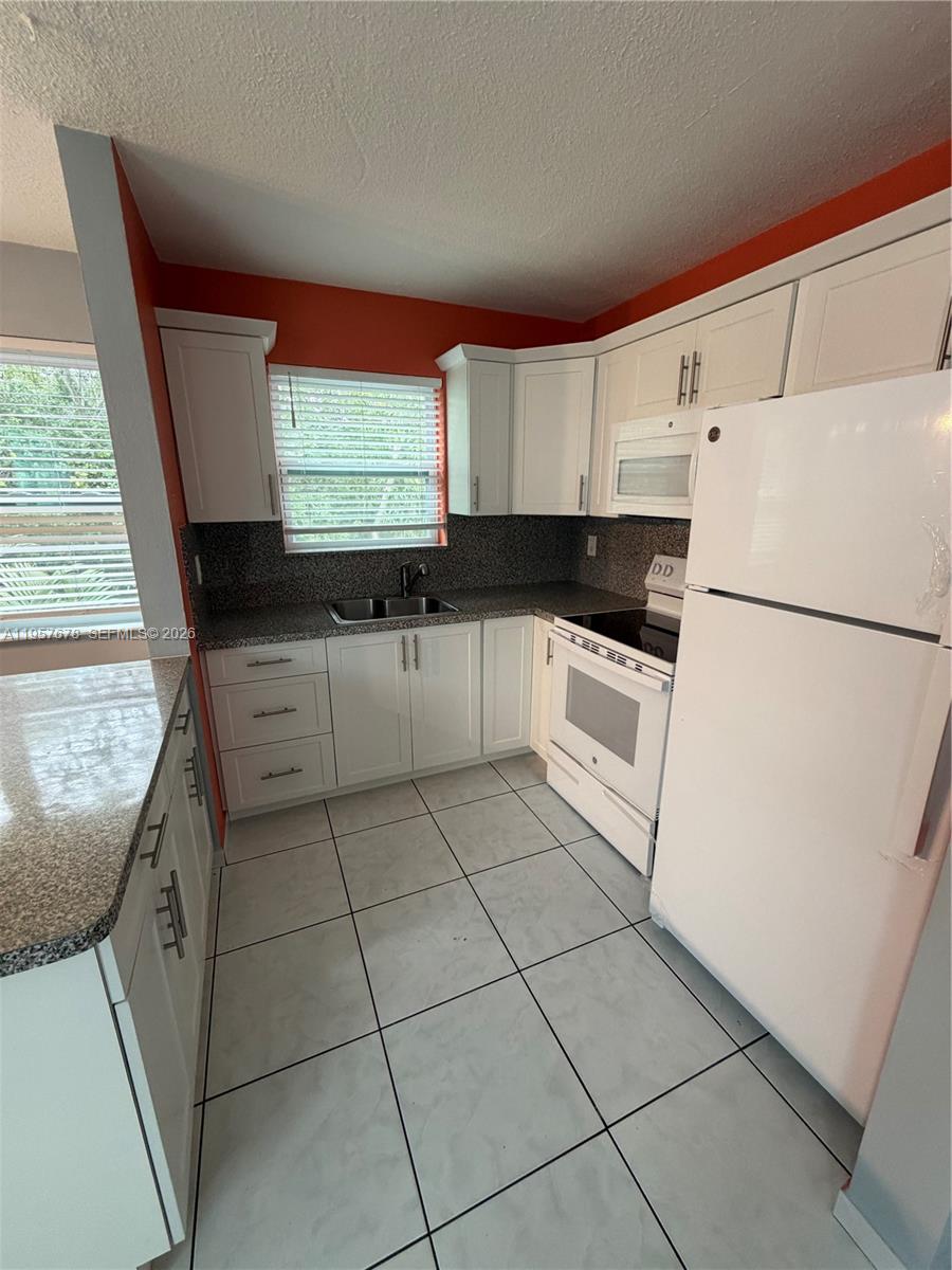 1301 North 12th Court, Unit 4B Hollywood, FL 33019 - Photo 12 of 27 a kitchen with granite countertop a sink a stove a refrigerator and cabinets