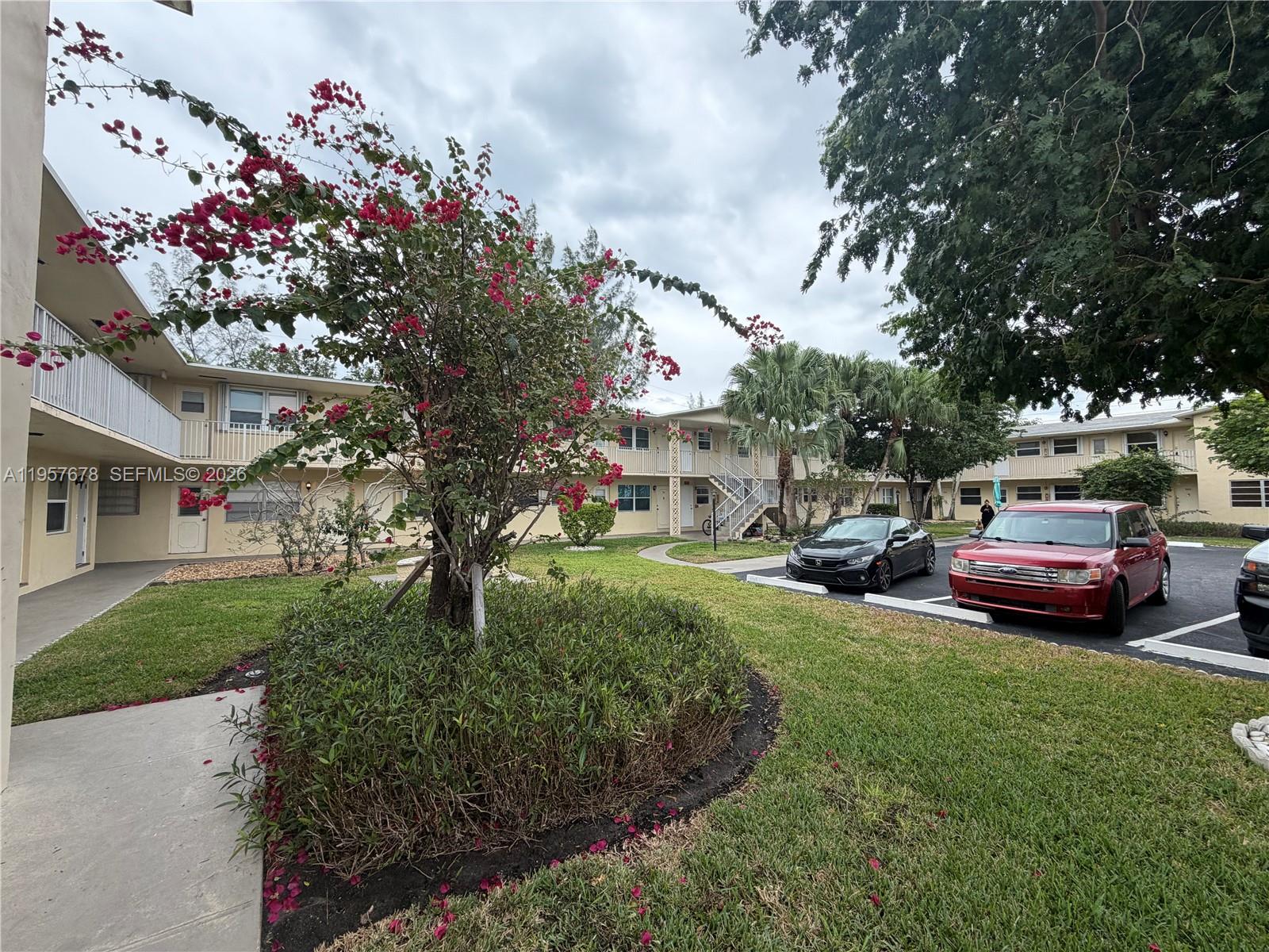 1301 North 12th Court, Unit 4B Hollywood, FL 33019 - Photo 2 of 27 a white house with a big yard and large trees
