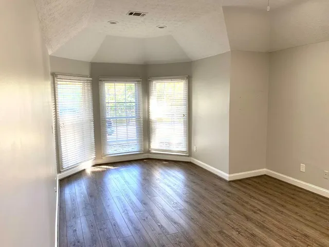 an empty room with wooden floor and windows
