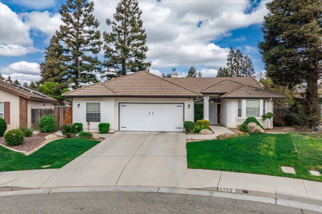 a front view of a house with a garden and trees