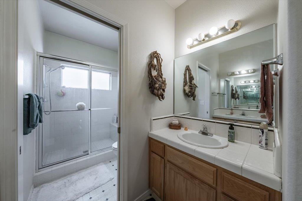 3159 Cedar Creek Lane Madera, CA 93637 - Photo 12 of 37 a bathroom with a shower sink and mirror
