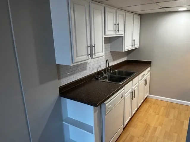 a kitchen with granite countertop white cabinets and black appliances