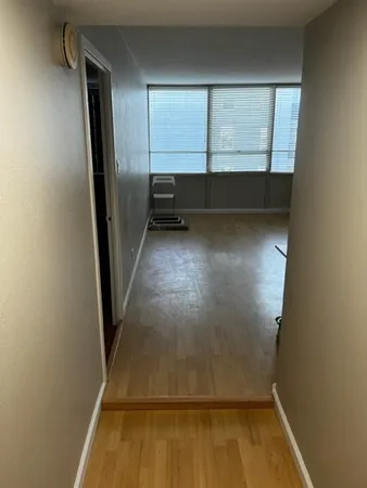 a view of an empty room with wooden floor and a window