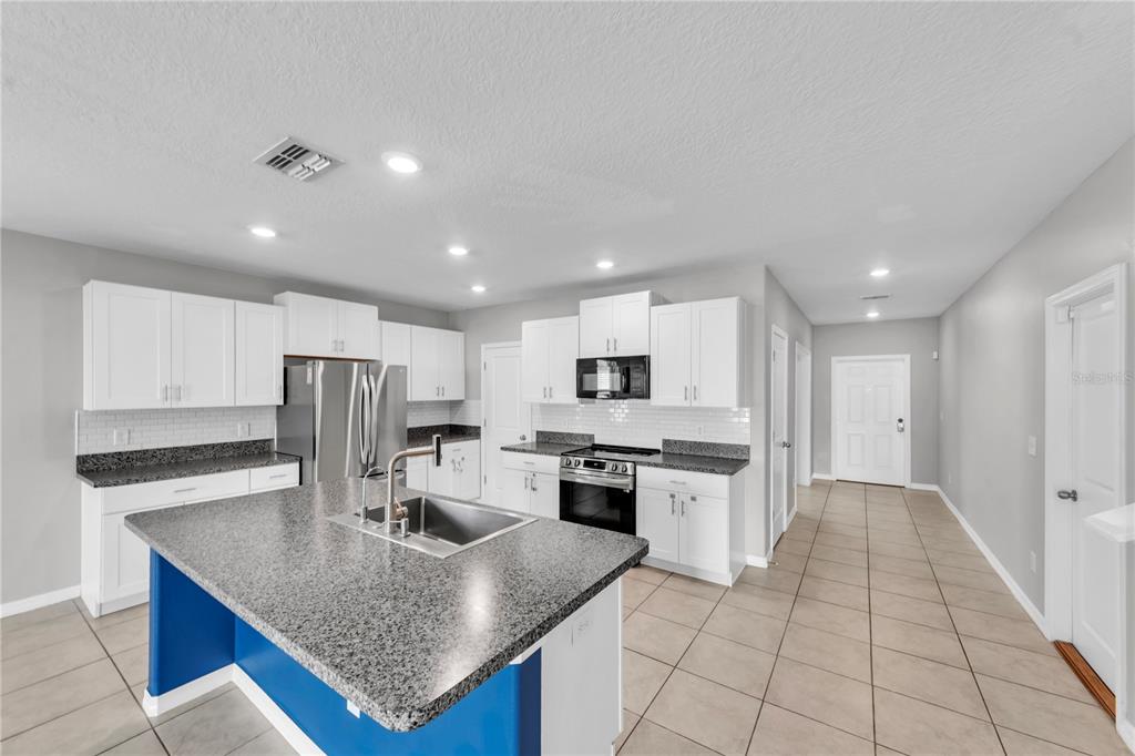 4215 Hanover Drive New Port Richey, FL 34653 - Photo 5 of 46 a kitchen with kitchen island granite countertop a stove top oven a sink dishwasher a refrigerator and white cabinets with wooden floor