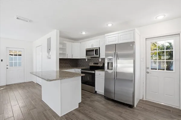 a kitchen with stainless steel appliances granite countertop a refrigerator and a stove top oven