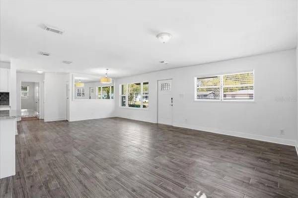 a view of an empty room with a window and wooden floor
