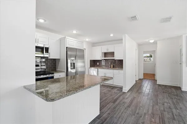 a kitchen with stainless steel appliances granite countertop a refrigerator a sink a stove and cabinets