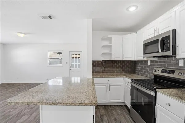 a kitchen with stainless steel appliances granite countertop a sink stove and microwave