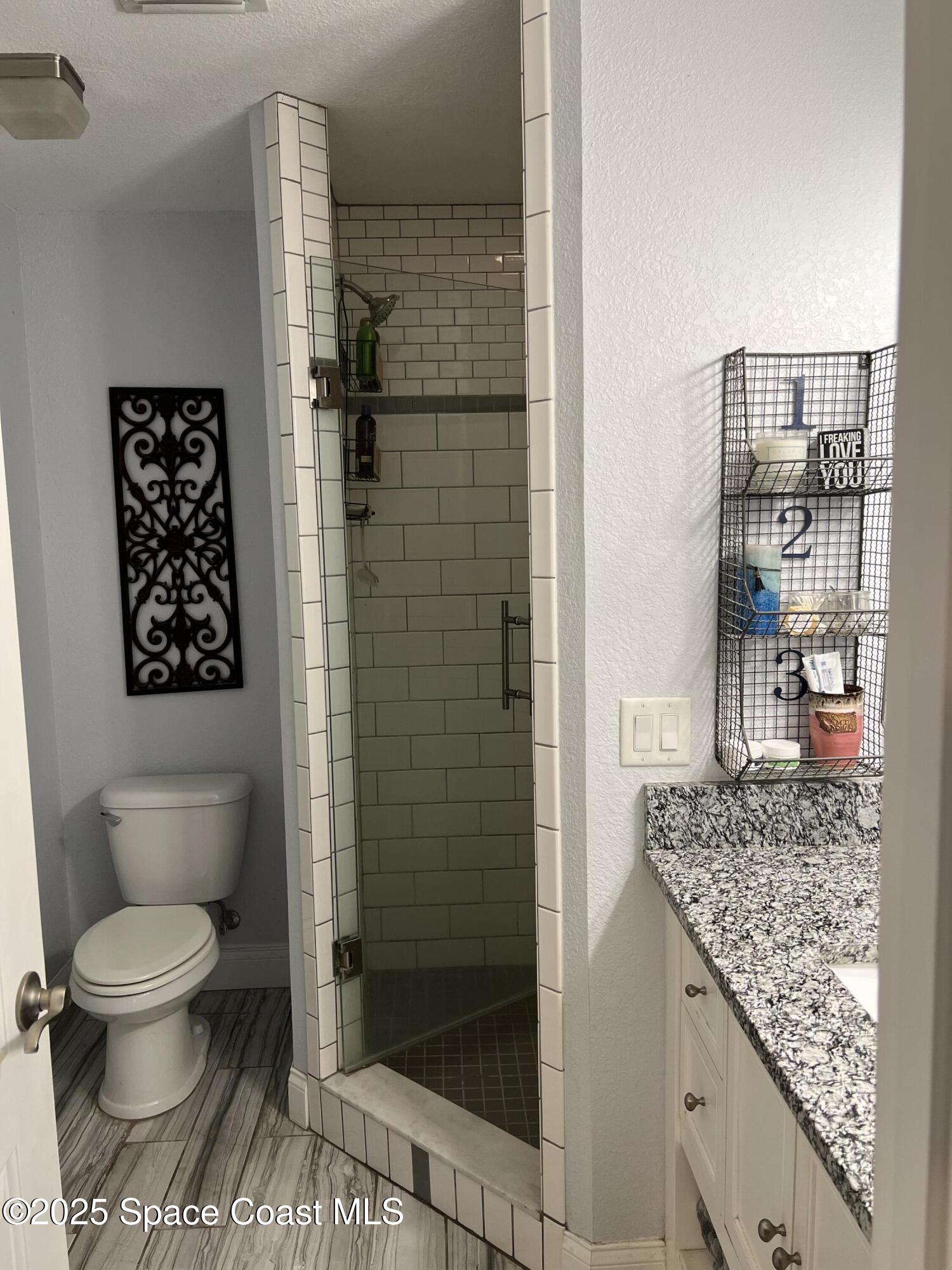 821 Hanover Court Rockledge, FL 32955 - Photo 7 of 15 a bathroom with a granite countertop toilet and a shower