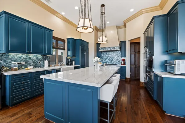 a living room with stainless steel appliances furniture a rug and a kitchen