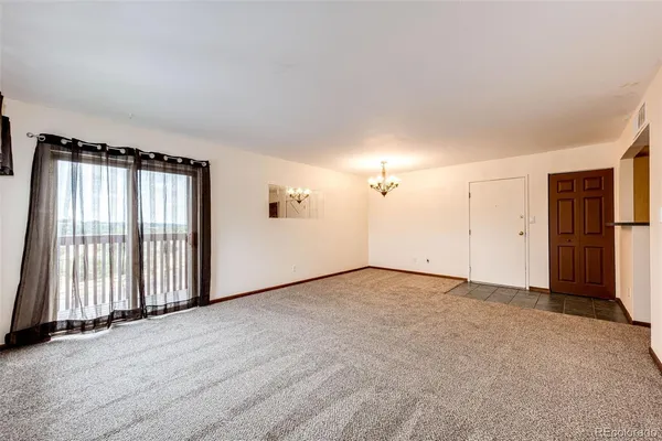 an empty room with windows and refrigerator