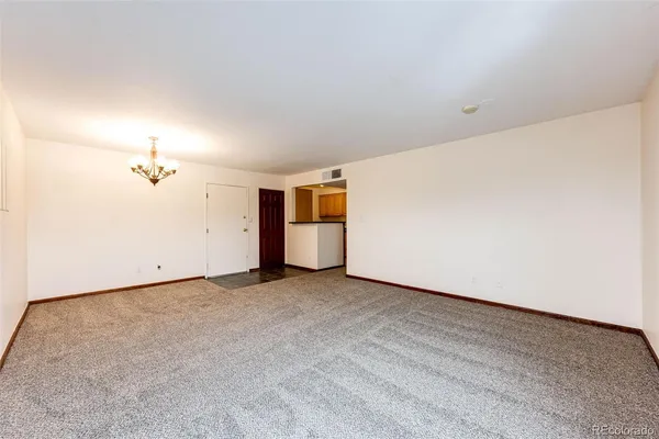 a view of a hallway with wooden floor and a kitchen