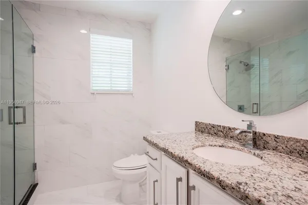 a bathroom with a granite countertop sink toilet and a mirror