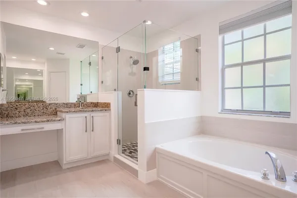 a bathroom with a bathtub a sink a window and a shower